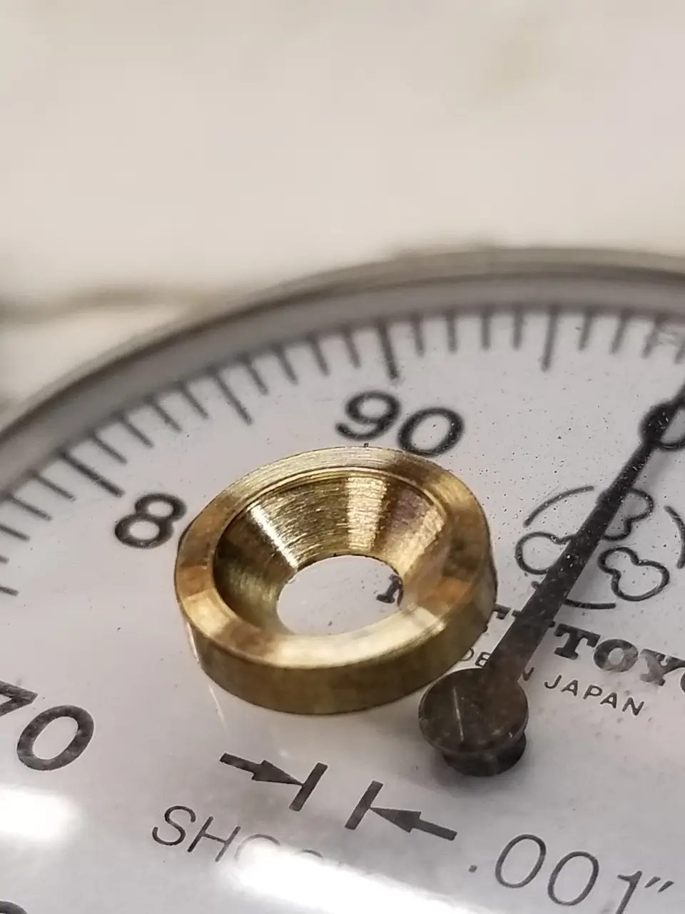 Brass part beside a precision indicator