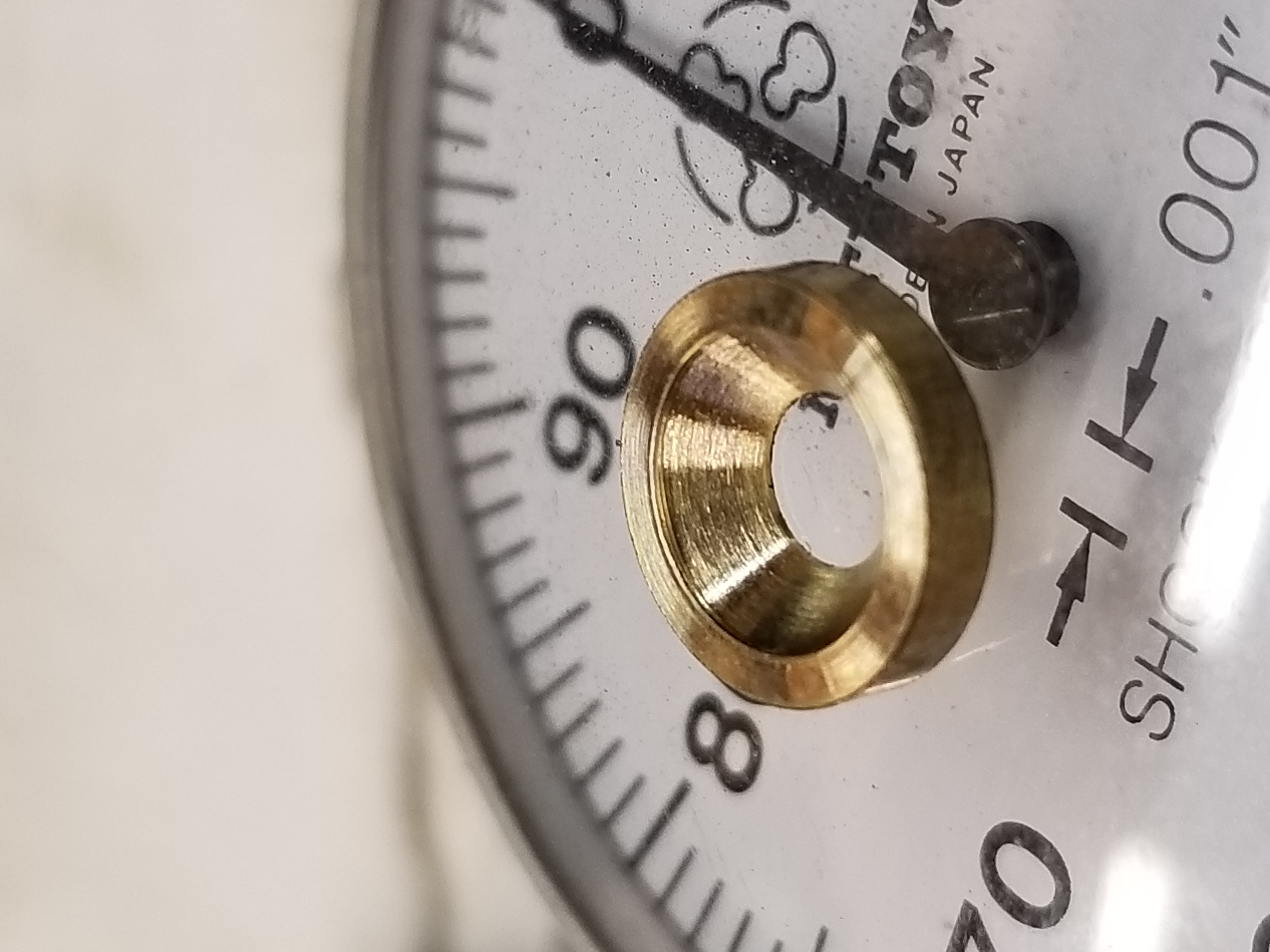 Brass part beside a precision indicator